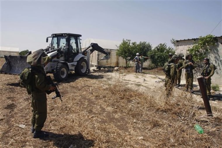 Israeli soldiers guard as a military tractor destroy wells used by Palestinian farmers for agricultural irrigation near the West Bank village of Kfar Dan west of Jenin, on Sunday. The Israeli military says the wells were drilled illegally and endanger an underground aquifer. 